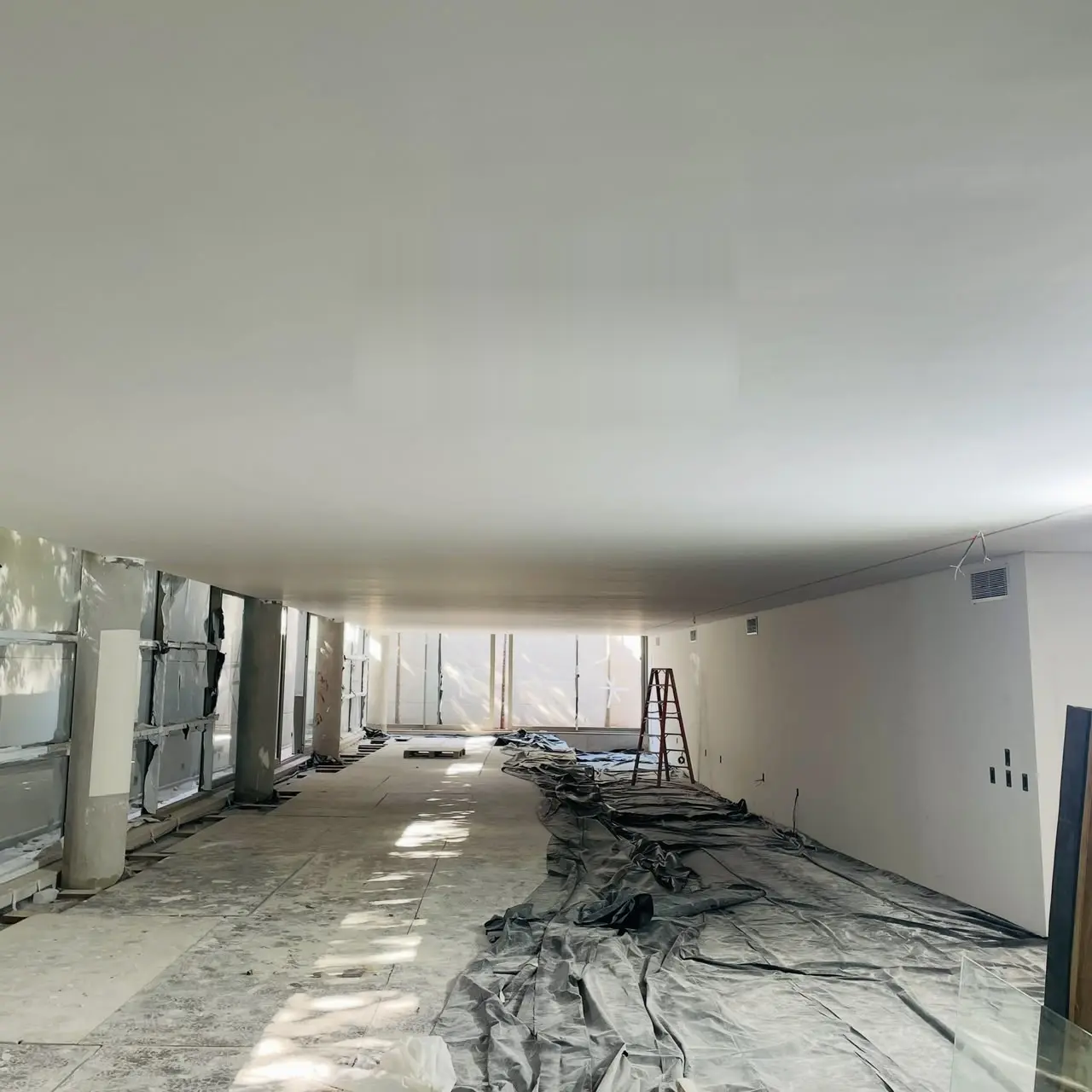 Teto de concreto aparente ainda em obra, sem revestimento, com piso protegido por lona